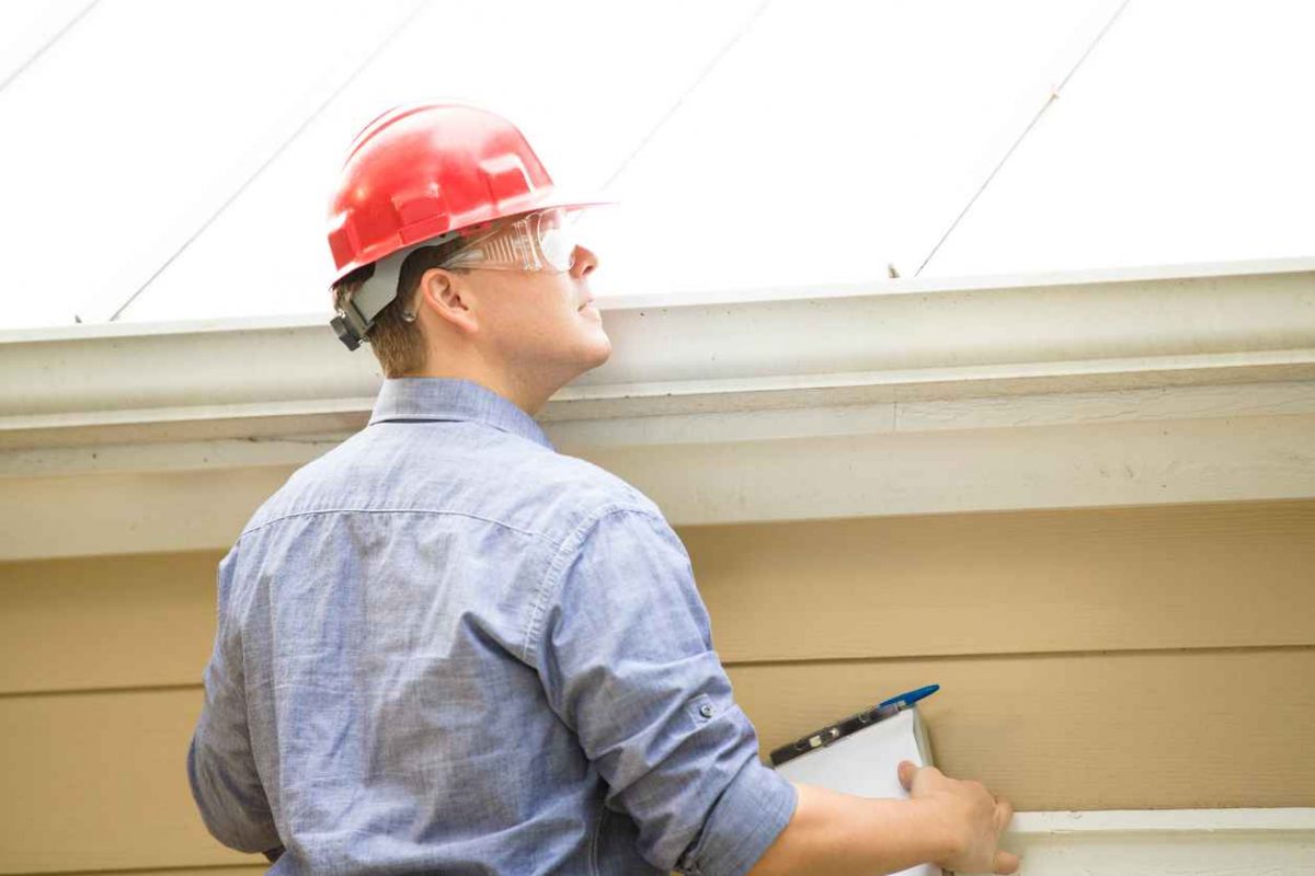 Inspector examining a metal residential roof for a professional inspection